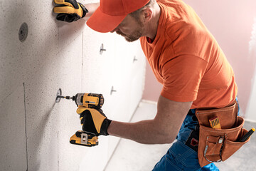 The worker`s hand using impact wrench do during anchoring a mineral insulation board with a...