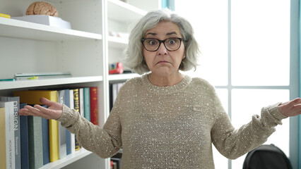 Middle age woman with grey hair teacher standing with i dont know expression at university classroom