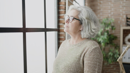 Middle age woman with grey hair business worker standing with relaxed expression at office