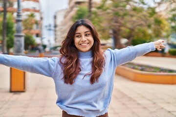Young hispanic woman smiling confident standing with open arms at park