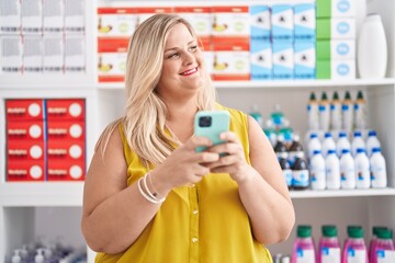 Fototapeta na wymiar Young woman customer smiling confident using smartphone at pharmacy