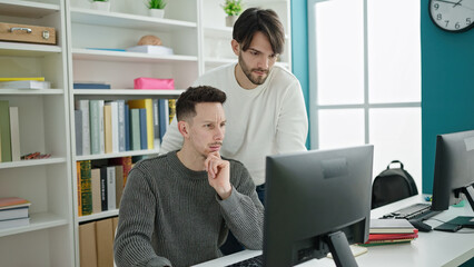 Two men students using computer studying at library university
