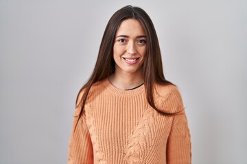 Young brunette woman standing over white background with a happy and cool smile on face. lucky person.