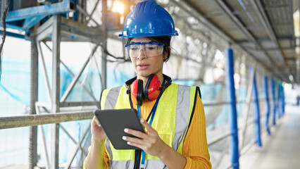 Young beautiful hispanic woman architect using touchpad at street