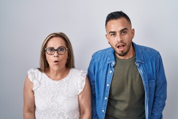 Hispanic mother and son standing together afraid and shocked with surprise and amazed expression, fear and excited face.