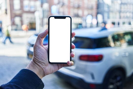 Man holding smartphone showing white blank screen at car parking