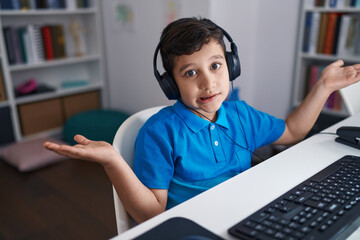 Little hispanic boy using computer laptop at the school celebrating achievement with happy smile and winner expression with raised hand