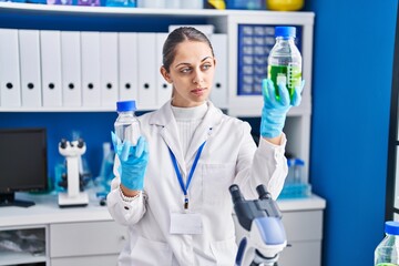 Fototapeta premium Young woman scientist holding bottles with liquid at laboratory