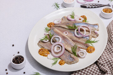 Salted herring with dijon mustard, dill and red onion rings on white stone background