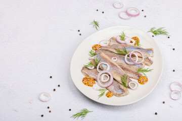 Salted herring with dijon mustard, dill and red onion rings. Marinated filleted fish on light stone