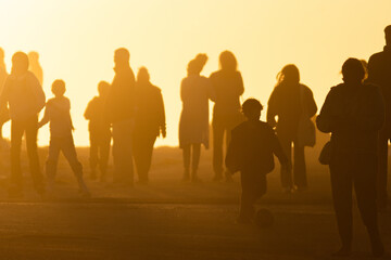 Silhouette of a crowd of people going towards the yellow bright sunset