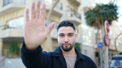 Young arab man doing stop gesture with hand at street