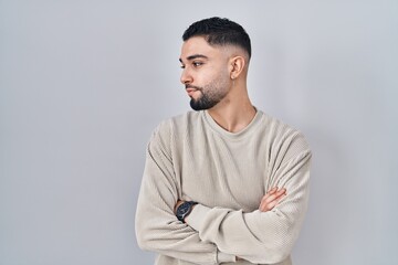 Young handsome man standing over isolated background looking to the side with arms crossed convinced and confident