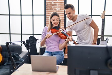 Man and woman musicians having online violin lesson at music studio
