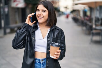 Fototapeta premium Young beautiful hispanic woman talking on the smartphone drinking coffee at street