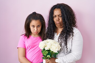 Mother and young daughter holding bouquet of white flowers depressed and worry for distress, crying angry and afraid. sad expression.