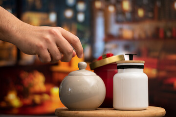 Hand open a Mug of sugar and salt containers style vintage over a table in night restaurant with selective focus and bokeh background