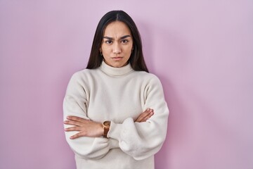Young south asian woman standing over pink background skeptic and nervous, disapproving expression...