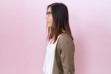 Middle age chinese woman wearing glasses over pink background looking to side, relax profile pose...