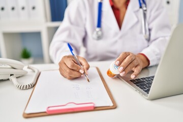 Fototapeta premium Middle age hispanic woman wearing doctor uniform prescribe pills at clinic