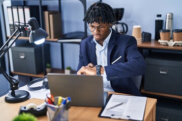 African american man business worker using laptop and looking watch at office