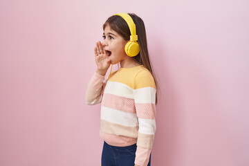 Little hispanic girl listening to music using headphones clueless and confused with open arms, no idea and doubtful face.