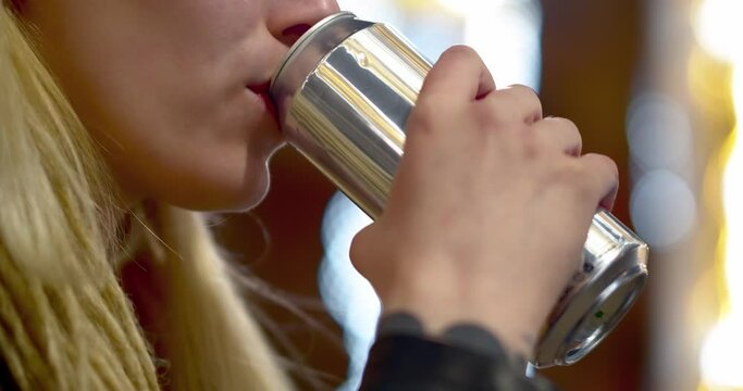 Teenage girl drinking energy drink from can - lips close-up.