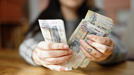 Hands of woman counting peruvian soles banknotes at room