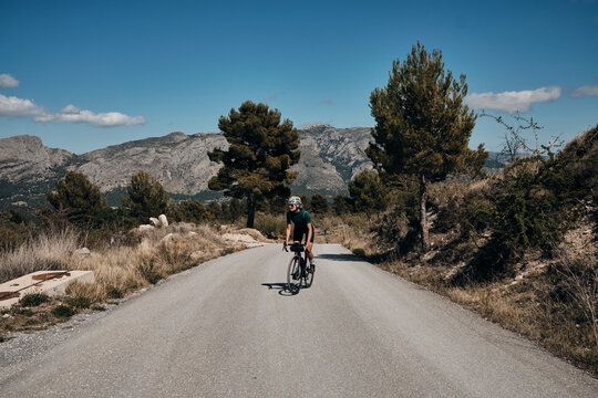 Woman cyclist riding a gravel bike with a view of the spanish mountains.Fit athlete wearing sportswear and helmet. Sports motivation image.