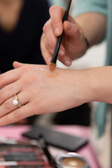 A female makeup artist applying shiny shadows on her hand