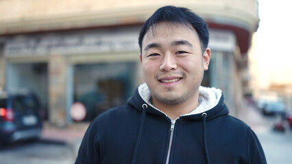 Young chinese man smiling confident standing at street