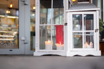 Eco-friendly white wooden houses for outdoor candles. The entrance to the cafe in the background. Copy space