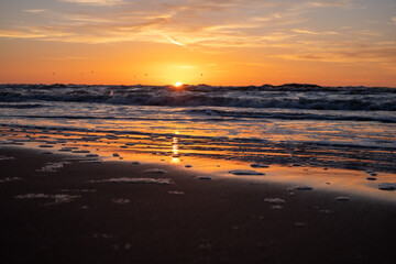 Obraz premium A gorgeous, meditative, colorful sunset on the seashore at the end of winter in the background. The sea, the horizon and the path of the sun.