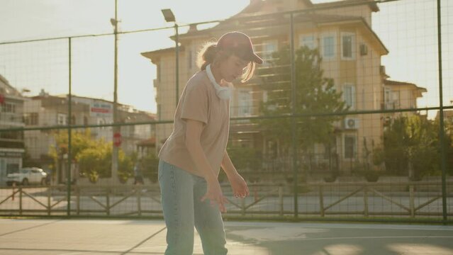 An 11-year-old girl plays basketball on a street basketball court. Ideal for sports and an active lifestyle