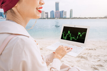 Young woman working on laptop with stock market exchange and cryptocurrency online graph and chart,...
