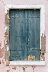 Obraz na płótnie Canvas Colourful window shutters in Burano Venice, Italy. rustic weathered pink and blue colours. Typical colourful Italian door and window housing