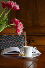 Reading  a book with a cup of tea/coffee in a classical interior and enjoying the beauty of the Peony tulips