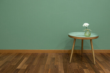 Innenausstattung eines Raumes mit einem kleinen, runden, grünen Tisch auf dem eine Vase mit ...