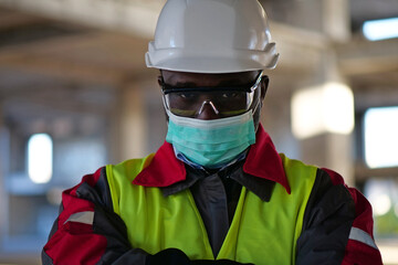 African american worker in mask stands at construction site, look at camera
