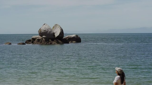 Woman admiring famous Split Apple Rock in Abel Tasman. New Zealand