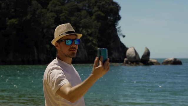 Caucasian man taking selfie with mobile at Split Apple Rock, Abel Tasman National Park. New Zealand