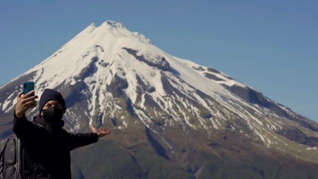 Caucasian man wearing face mask is taking picture with mobile at Mount Taranaki. New Zealand