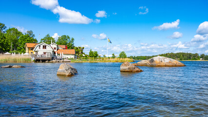 Sunny day in a small village bay on Vaxholm Island. On the coast is the Hembygdsgard Museum and a...