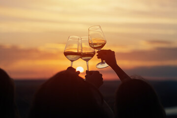 A group of girlfriends raise a toast with glasses of white wine on a sunset. Close shot.	
 - obrazy, fototapety, plakaty