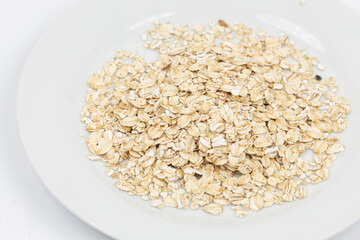 Dry rolled oatmeal in bowl isolated on white background. Top view.