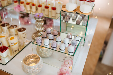 Delicious wedding reception candy bar dessert table full with cakes and sweets and flowers Chinese cherry blossoms on the background of an exquisite restaurant