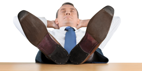 Portrait of happy businessman relaxing on chair with legs on table on background