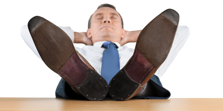 Portrait of happy businessman relaxing on chair with legs on table on background