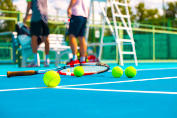 Tennis racket and tennis balls on hard blue court