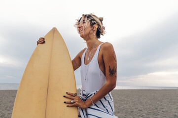 Portrait of a surfer woman posing with surfboard on a beach